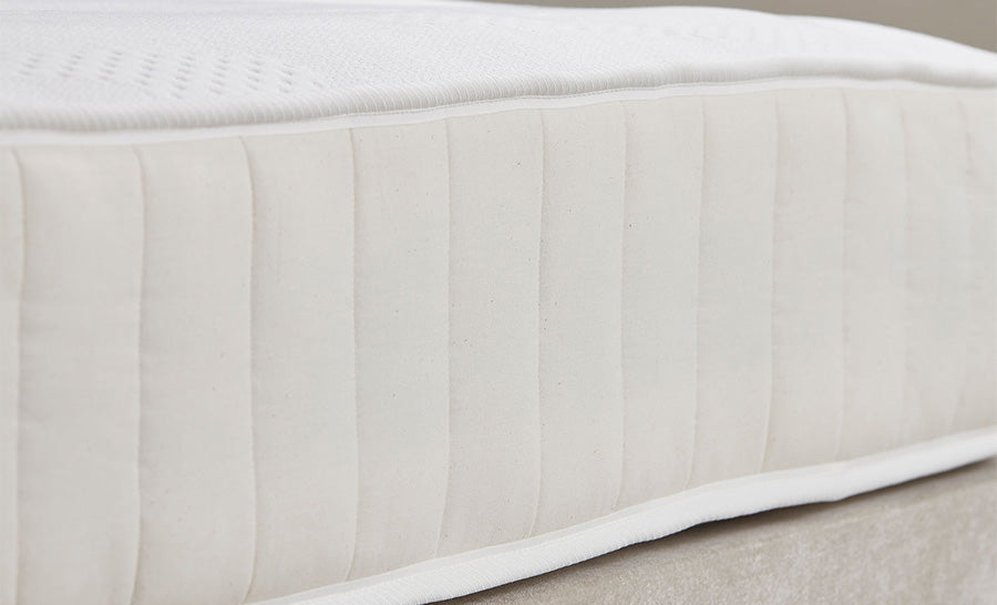 A close-up view of a mattress side resting on Single Ottomans, showing its soft, light fabric and stitched design.